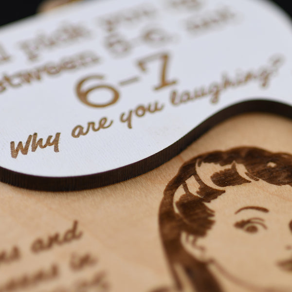 Close-up of a wooden ornament with engraved text and a portrait, featuring a vintage-style illustration.