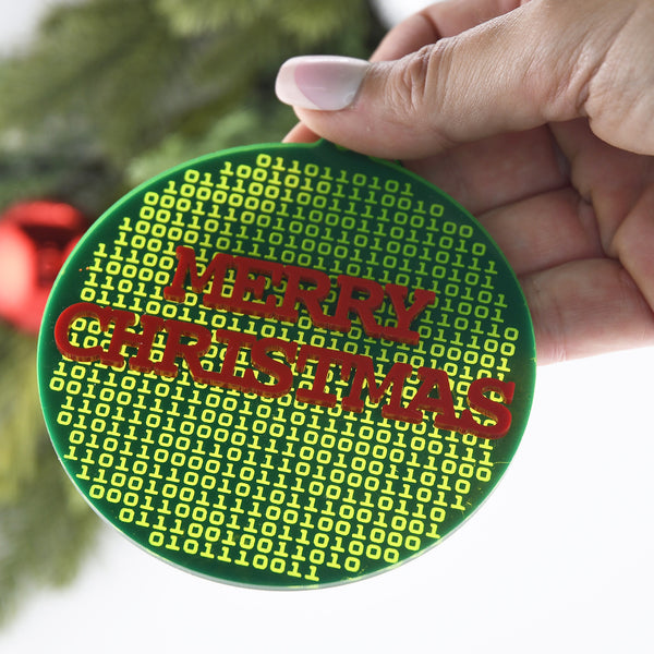 Circular ornament with 'Merry Christmas' text in red on a green background, held by a hand.