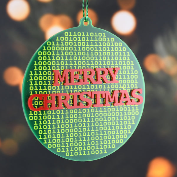 Decorative ornament with 'Merry Christmas' text in binary code on a blurred festive background.