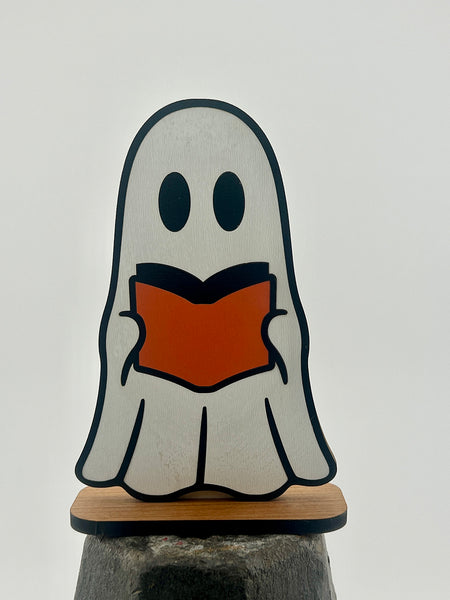 Ghost figurine holding a book on a white background