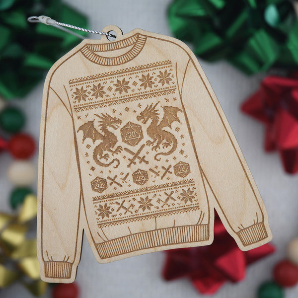 Wood engraved sweater ornament with a design featuring a D20 die and dragons, against a blurred holiday background