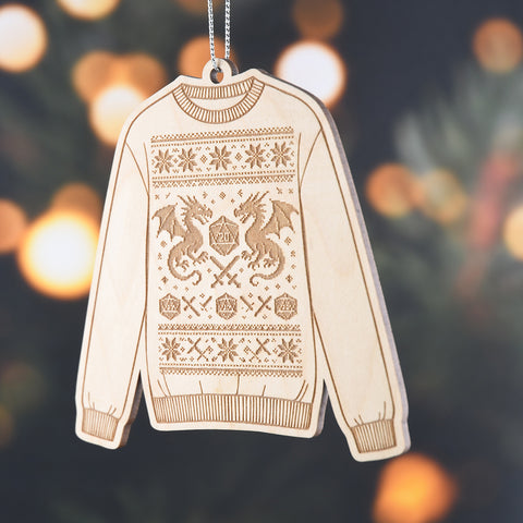 Wood engraved sweater ornament with a design featuring a D20 die and dragons, against a blurred holiday background