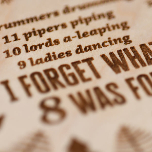 Close up detail of wood laser engraved ornament saying "I forget what 8 was for"
