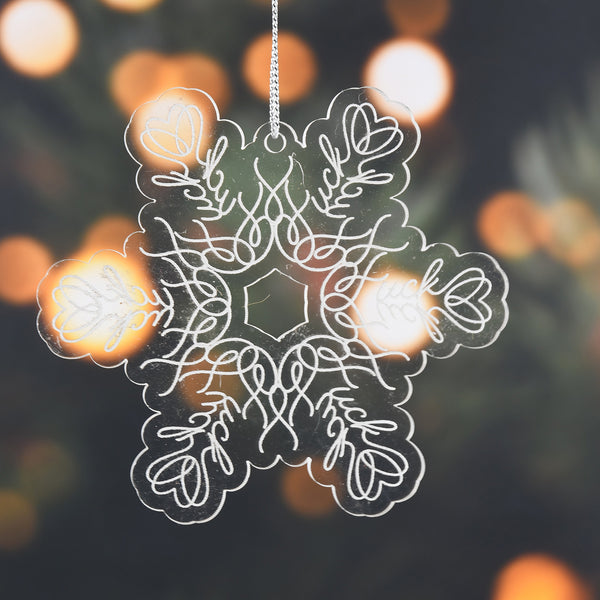 Acrylic ornament with hidden "fuck" words, on a blurred tree background