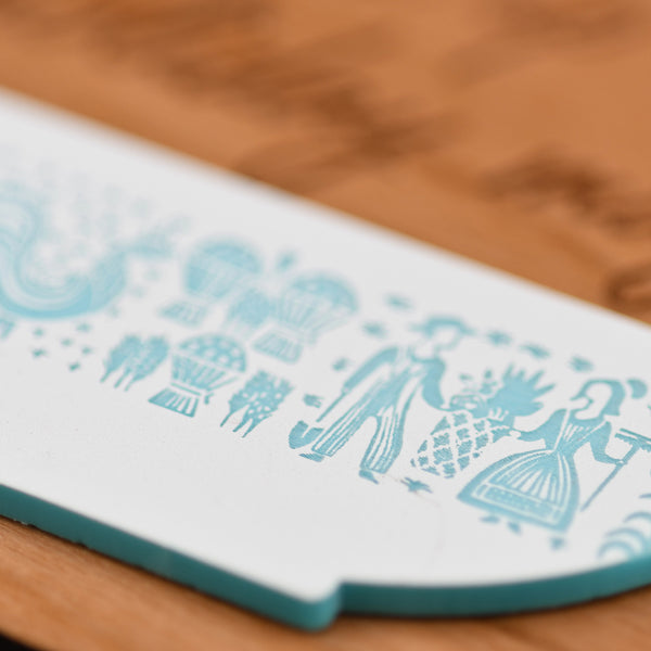 Close-up of a white cutting board with blue decorative patterns on a wooden surface