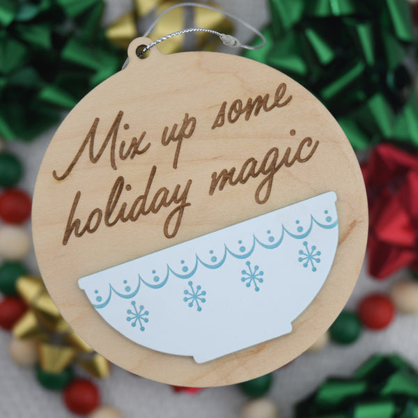 Wood and acrylic ornament with "Mix up some holiday magic" on blurred bow background