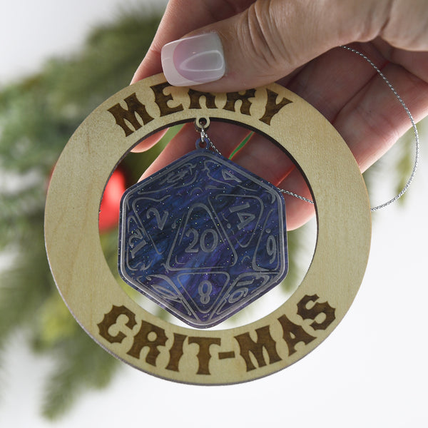 Decorative Christmas ornament with purple die and 'Merry Crit-Mas' text, held by a hand.