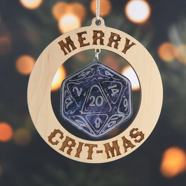 Wooden ornament with a die design and 'Merry Crit-Mas' text against a blurred Christmas tree background.