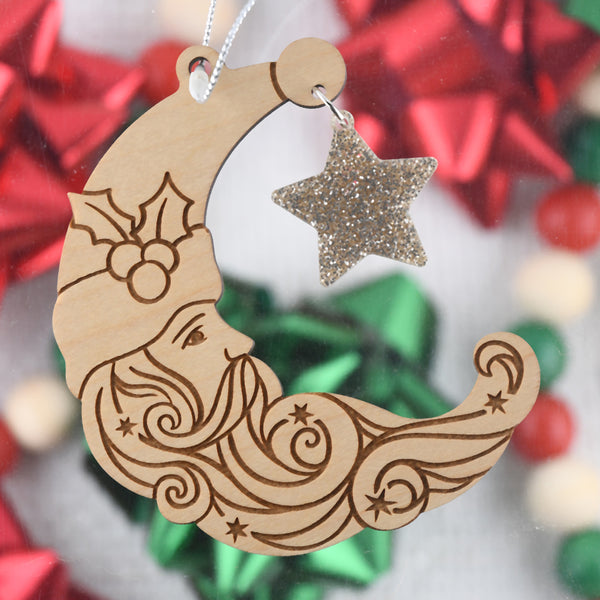 Decorative wooden ornament shaped like a crescent moon with a face and a star, against a festive background.