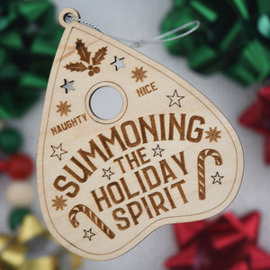 Wooden ornament with 'Summoning the Holiday Spirit' text on a blurred festive background