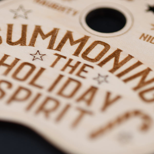 Close-up of a wooden tag with text 'Summoning the holiday spirit' on a blurred background.