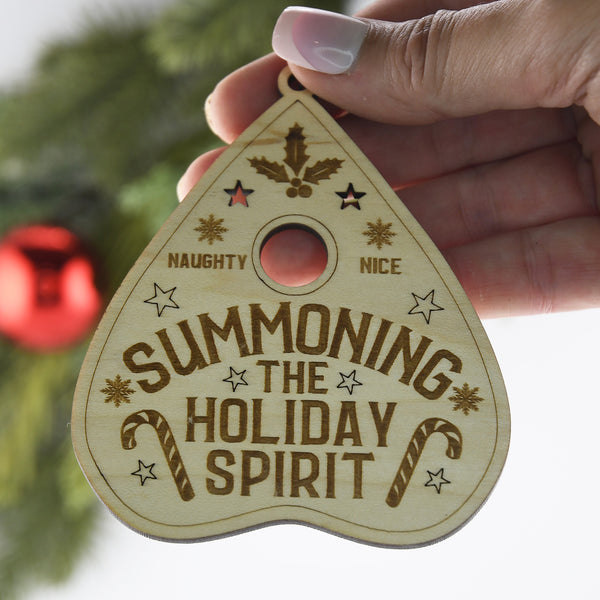 Wooden ornament with 'Summoning the Holiday Spirit' text held by a woman's hand